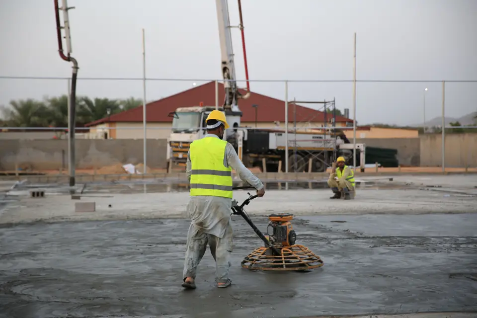 Workers power-troweling a newly placed concrete slab